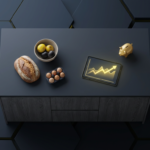 A dark kitchen sideboard with bread, eggs, fruit in bowls, a tablet showing a rising chart, and a small piggy bank on a hex-tiled backdrop.”] ,